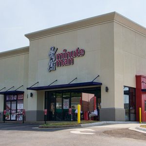 "Minute Man" business at end of strip mall with awnings on parking lot