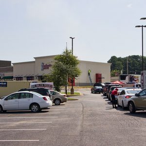 Line of cars and parked cars in strip mall parking lot