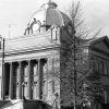 Multistory brick building with large front steps greek columns entablature large dome and trees