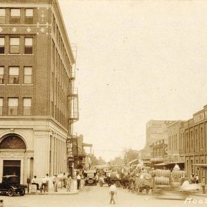 People and cars on crowded street between rows of multistory buildings