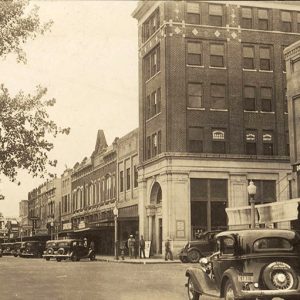 Cars driving past multistory buildings on town street