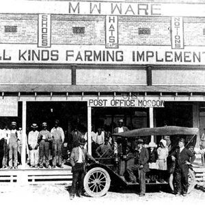 White crowd at brick storefront with car