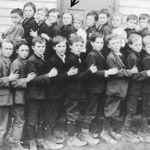 Group of white children standing outside building with wood siding