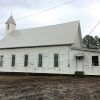 Side view of white wooden church building with steeple