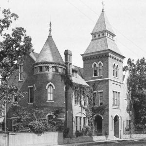 Three-story building with towers, arched entrances, and arched windows