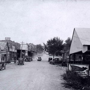 Cars trucks and town buildings on dirt road