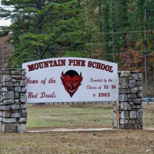 Stone columns with white sign with red text and devil face painted on it and the words "home of the red devils donated by the classes of 93-94 and 2003"