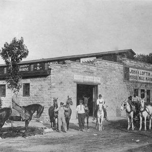 White and African-American men with horses and carriage outside of brick building