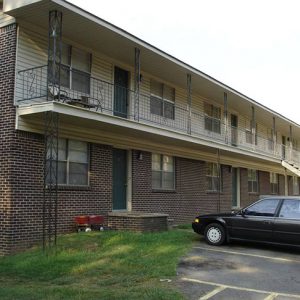 Two-story brick apartment building and parking lot with cars