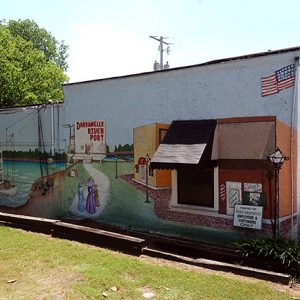 Mural with steamboat and town painted on brick building