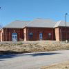 Single-story brick building with arched windows and parking lot