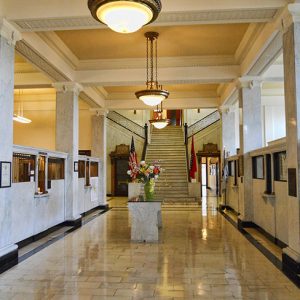 Hallway with columns hanging lighting fixtures and staircase in the background