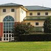 Multistory building with arched window above doors and green roof