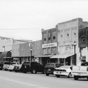 Two-story brick buildings on street with parked cars