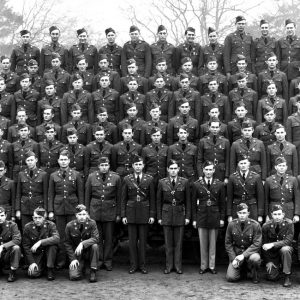 Group photo white male soldiers seven rows dress uniforms in field with flag "153 E"