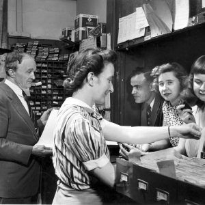 White man and woman talking to three white students through an office window