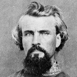 White man with wavy hair and beard in gray military uniform