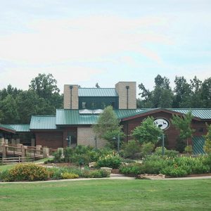 Multistory building with wood siding and green metal roof and flower gardens on grass