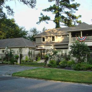 Two-story house with balcony behind an iron fence on street