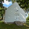 Single-story building with open gable roof and white siding