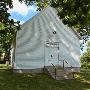 Single-story building with open gable roof and white siding