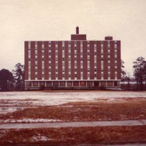 Eight-story rectangular building in winter with large field of snow covered grass