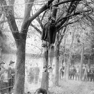 Postcard from "Bowen Art Gallery" in Newport depicting dead African-American suspended from noose in tree with white onlookers standing behind a fence