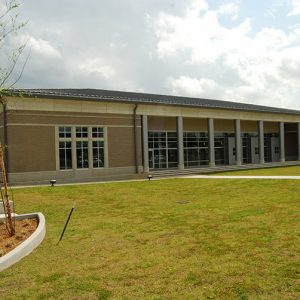 Single-story building with covered walkway on grass with sidewalk cutting across its front yard