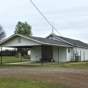 Single-story church building with steeple and covered front entrance