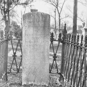 Engraved grave marker inside iron fence in cemetery