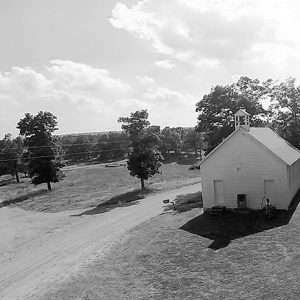 Aerial view of single-story chapel building with cupola at rural intersection