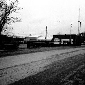 Dirt road with storefront and garage building in the background