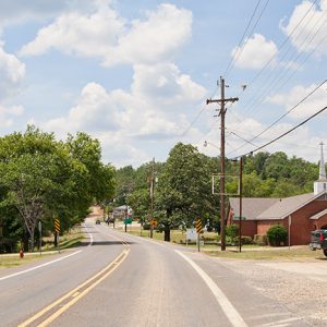 Street with house and brick church building with signs and power lines