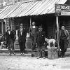 White men and dog standing on porch of building