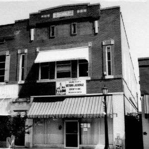 Close-up of multistory brick building with awnings over the sidewalk on street corner