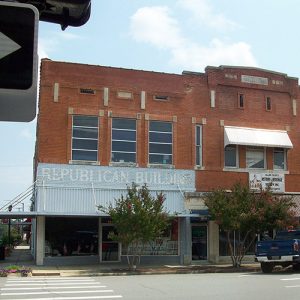 Multistory brick building with trees and parked truck on town street