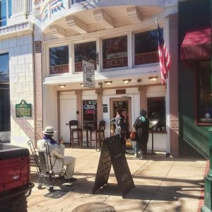 White women in coats talking outside restaurant with "Ohio Club" sign and Al Capone statue on bench