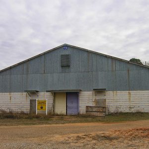 Weathered gray and white building and sign on dirt road