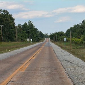 Two-lane highway with signs and trees on both sides