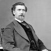 White man with beard in suit sitting in chair