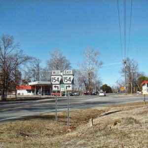 Street with road signs for Highway 154 and gas station with cars