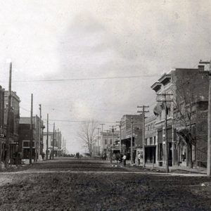 Dirt road with buildings and signs on both sides