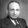 White man in glasses wearing a suit and vest