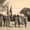 Young white men with flags in military uniform next to tiger statue