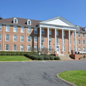 Multistory brick building with covered entrance supported by six columns