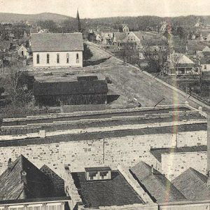 View overlooking brick storefront buildings and residential neighborhood with church on town streets