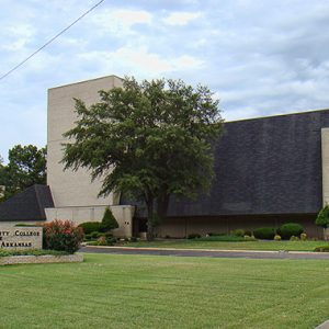 Brick and concrete building with trees and brick sign