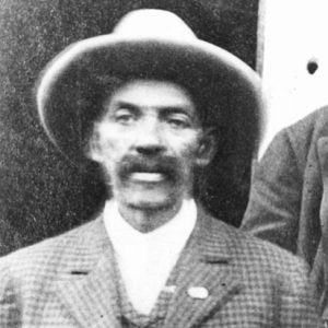 African-American man with thick wearing a hat in checkered suit