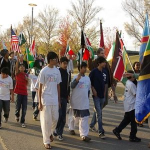 Mixed group of adults and children marching with flags of various nations on street