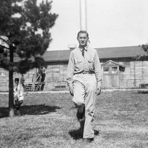 White man in suit with building and trees behind him